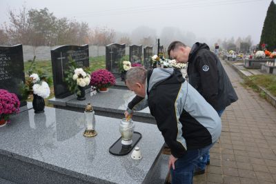 Pan Jerzy i Pan Maciej zapalają znicze na grobach naszych Mieszkańców.