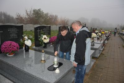 Pan Jerzy i Pan Maciej zapalają znicze na grobach naszych Mieszkańców.