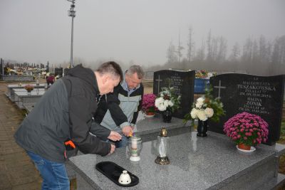 Pan Jerzy i Pan Maciej zapalają znicze na grobach naszych Mieszkańców.