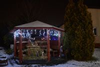 Bożonarodzeniowe lampki oświetlają też szopkę w ogrodowej altanie.